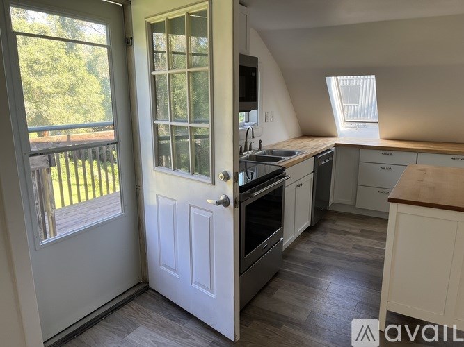 A kitchen with a white door and a window with a view of a deck.