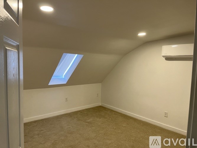 A room with a skylight and carpeted floor.