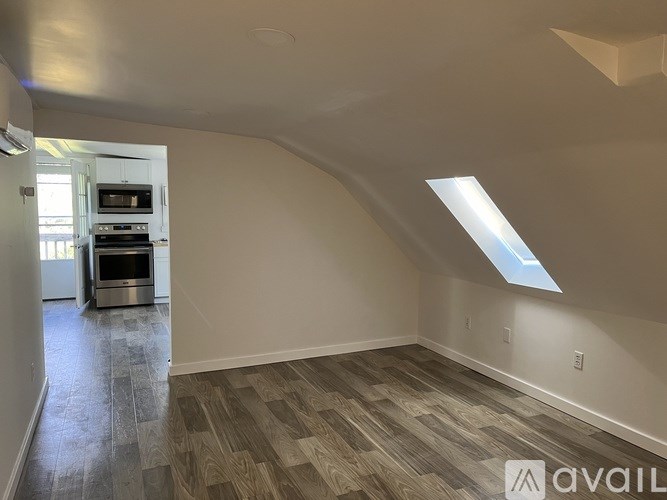 A spacious room with a skylight and wood flooring.