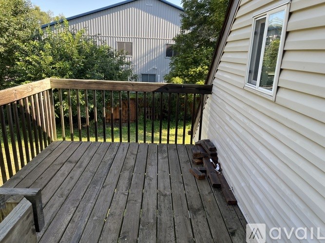 A wooden deck with a railing and a window on the side of a house.