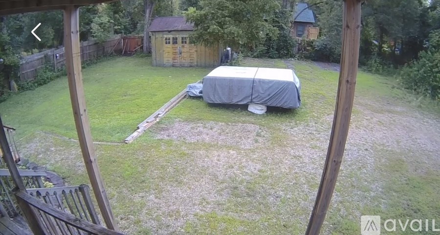 A backyard with a covered patio and a wooden fence.