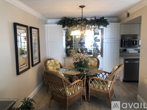 A dining room with a table set for four and a chandelier.