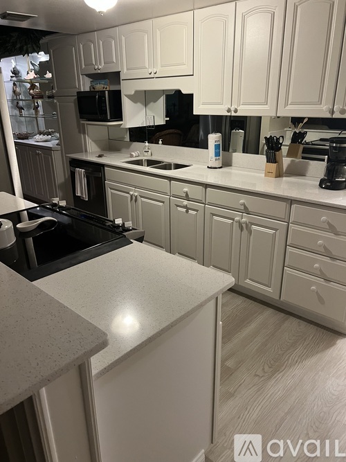 A kitchen with white cabinets and a granite counter.