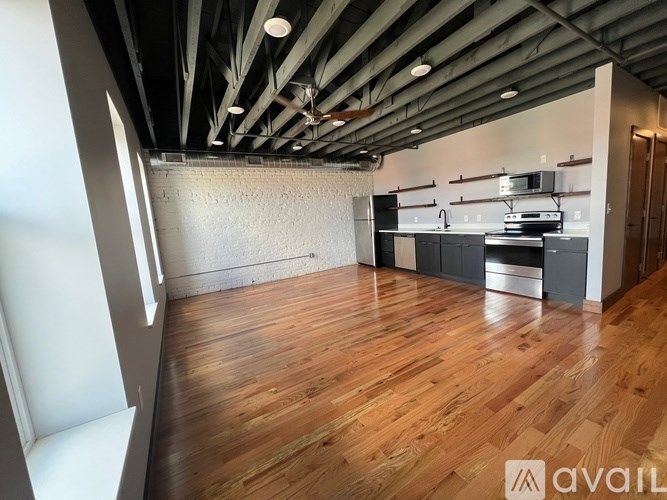 A spacious room with wooden floors and a high ceiling with exposed beams.