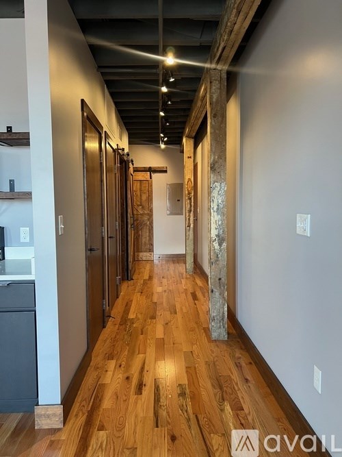 A long hallway with wood floors and a white wall on the right.