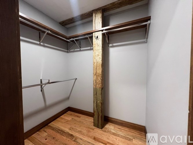 A wooden pole in a room with a white wall and a wooden floor.