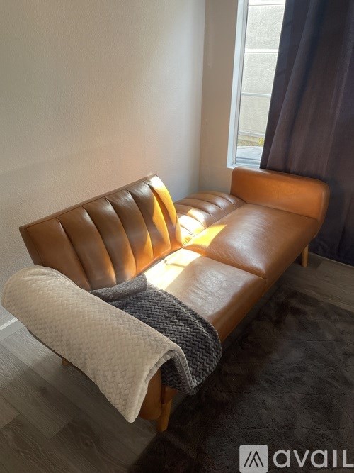 A brown leather sofa with a white blanket on it.