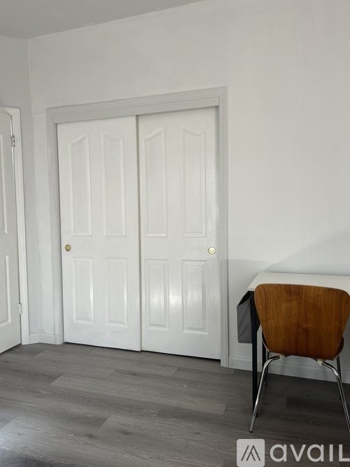 A room with a white door, a brown chair and a grey floor.