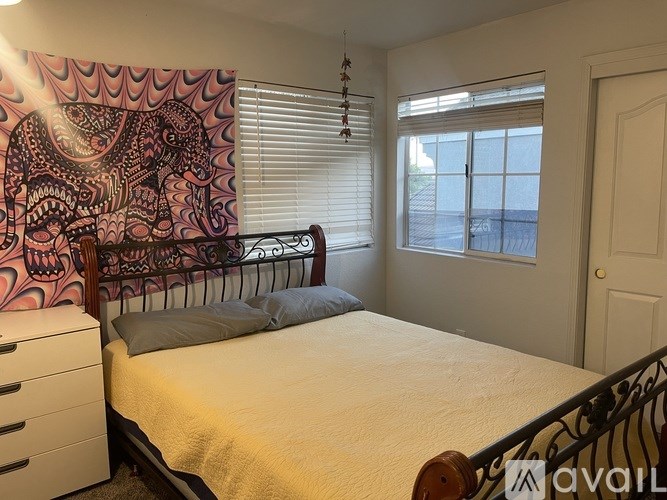 A bedroom with a bed, dresser, and a window with blinds.