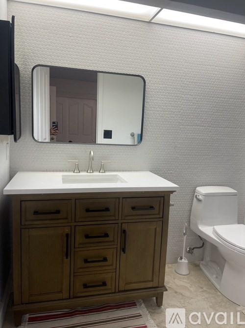 A bathroom with a sink, mirror, and toilet.