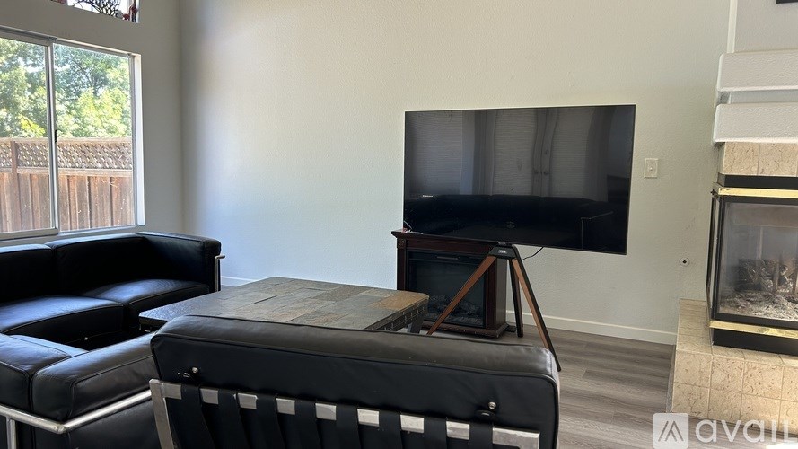A black leather sofa and chair in a room with a flat screen TV mounted on the wall.