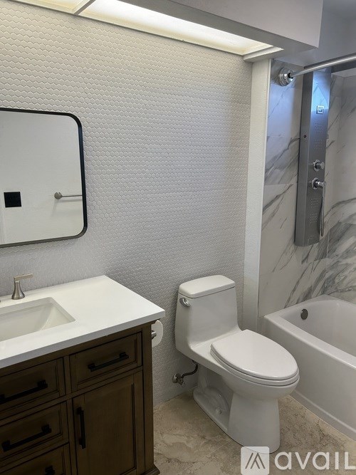 A white toilet in a bathroom with a sink and a bathtub.