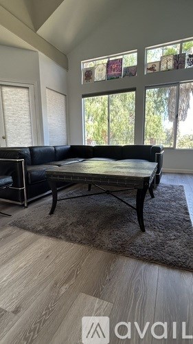 A living room with a black sofa and a glass table.