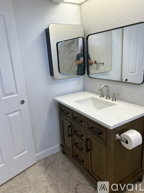 A bathroom with a white sink and brown drawers.