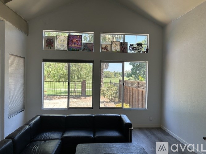 A living room with a black couch and pictures on the wall.