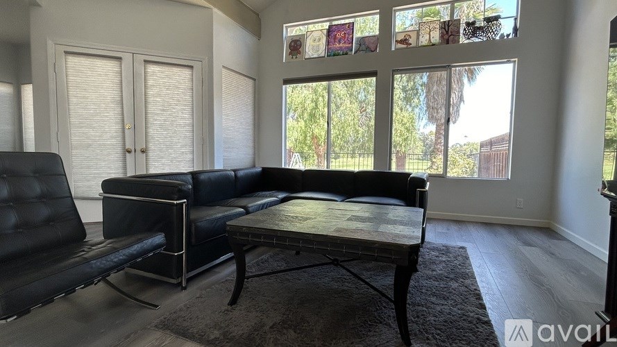 A black leather sofa sits in a room with a glass table and a rug.