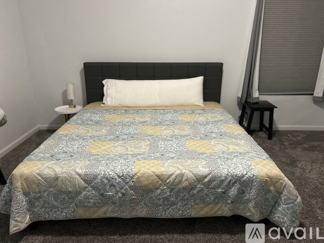 A bed with a blue and yellow comforter is in the image.