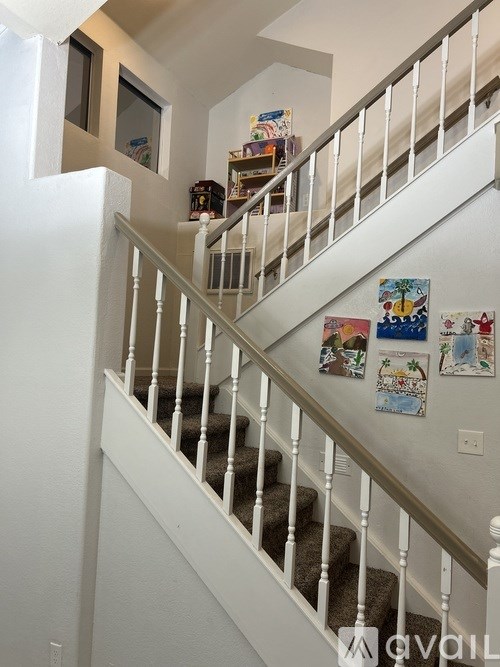 A staircase with a white railing and pictures on the wall.