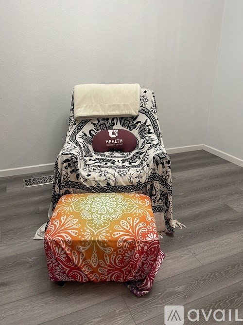 A black and white patterned chair with a pillow on top and a small stool with a colorful design in front of it.