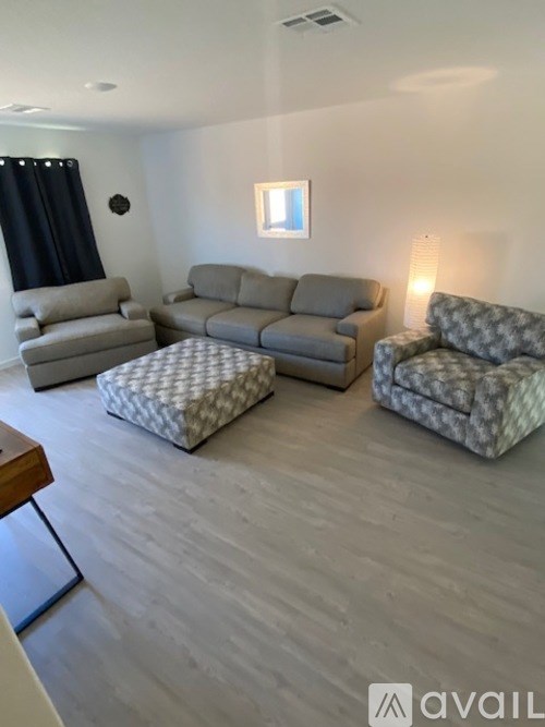 A living room with a grey sofa, two grey armchairs and a grey ottoman.