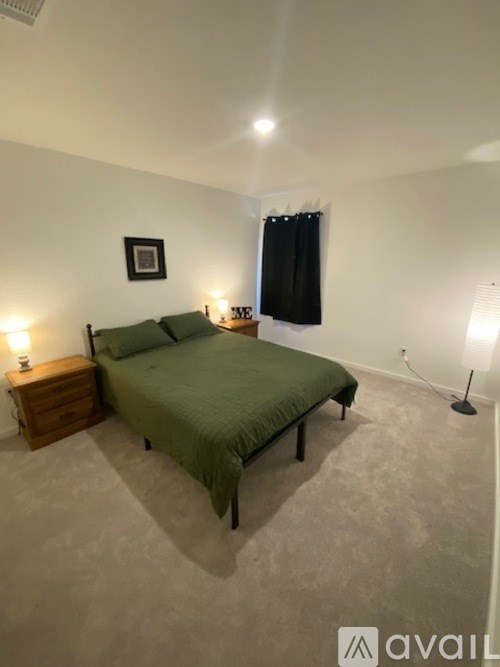 A bedroom with a bed, nightstand, and lamp.