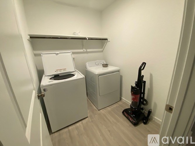 A small room with a toilet, a washing machine, and a vacuum cleaner.