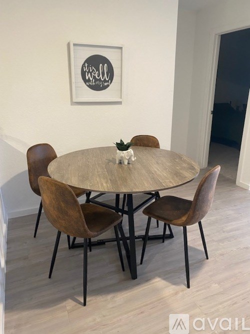 A round table with four chairs and a framed picture on the wall.