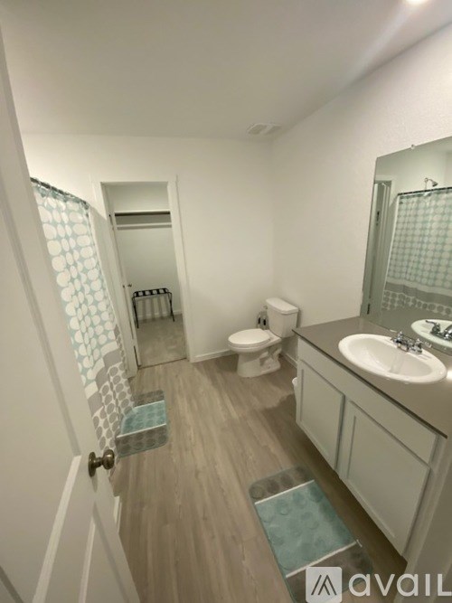 A bathroom with a toilet, sink, and mirror.
