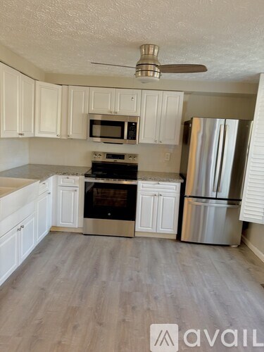 A kitchen with white cabinets and a stainless steel refrigerator.