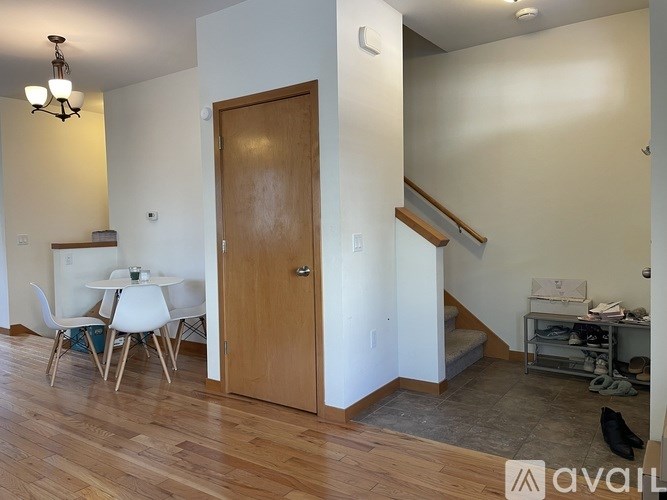 A room with a wooden door and a dining table with chairs.