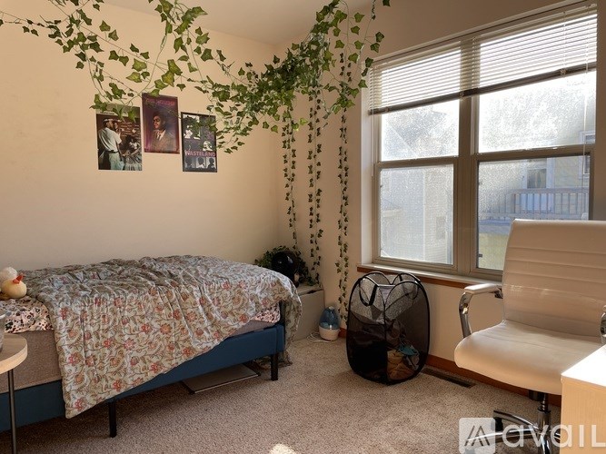 A bedroom with a bed, chair, and plants.