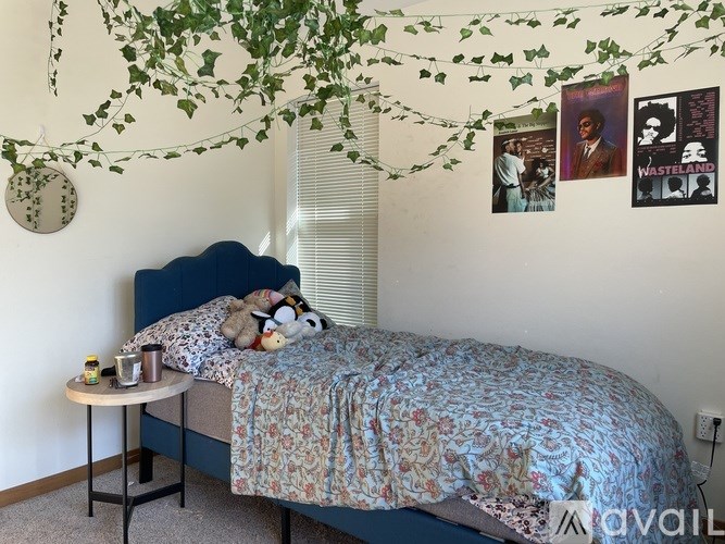 A bedroom with a bed, a small table, and a wall hanging with a picture of a man.