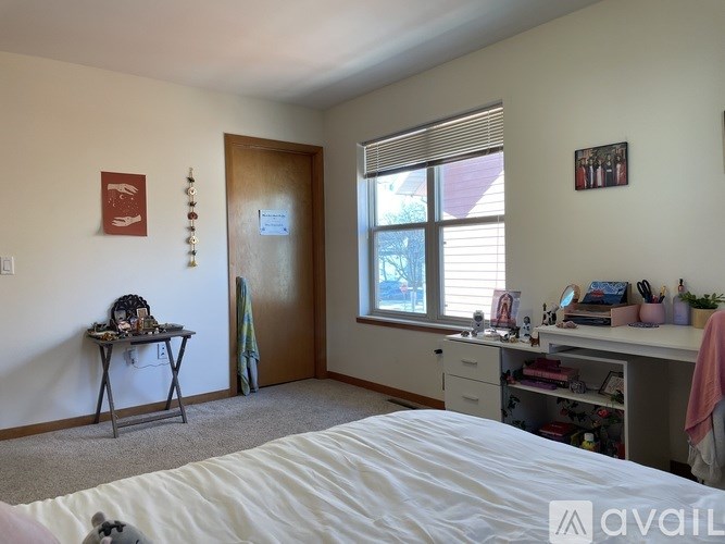 A bedroom with a bed, desk, and window.