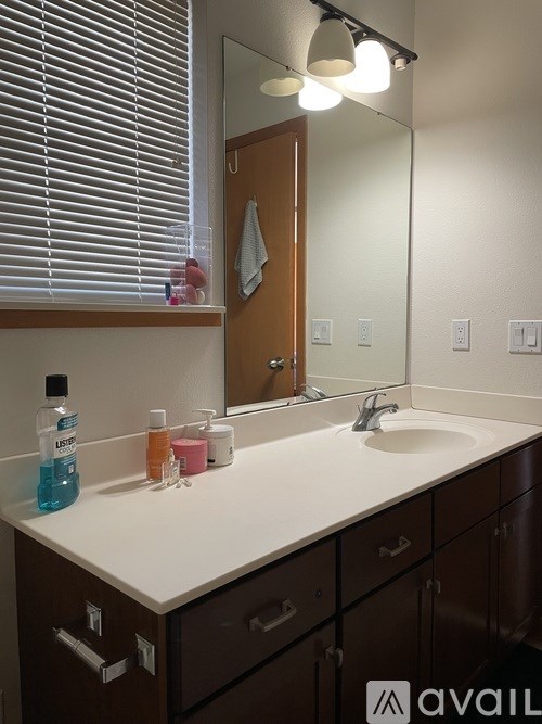 A bathroom with a white counter top and brown drawers.