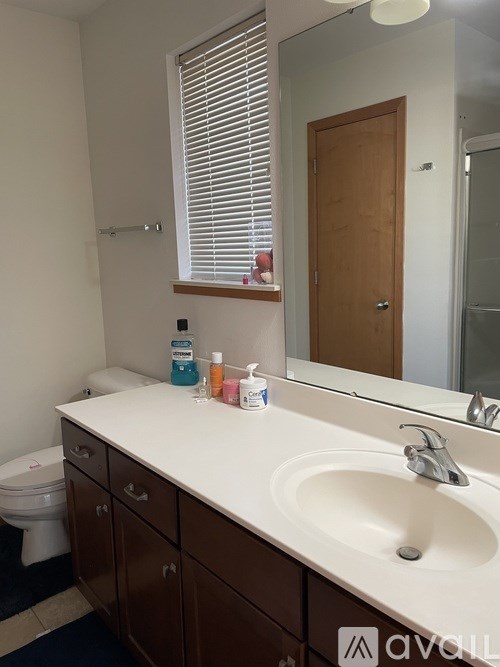 A bathroom with a white counter top and brown drawers.