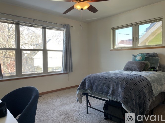 A bedroom with a bed, chair, and window.