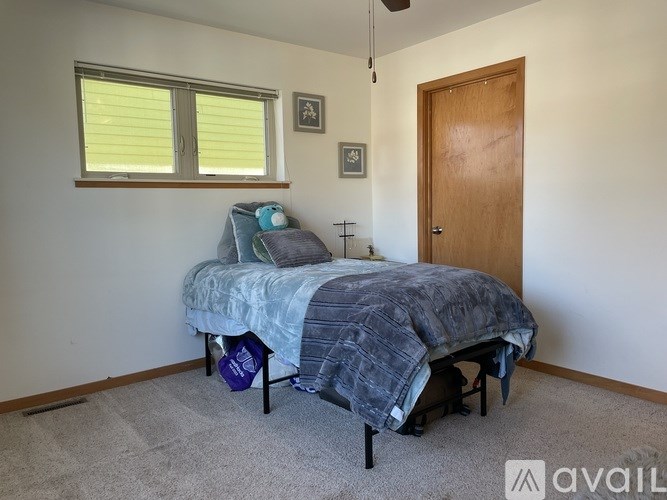 A bedroom with a bed, pillow, and a cross on the wall.