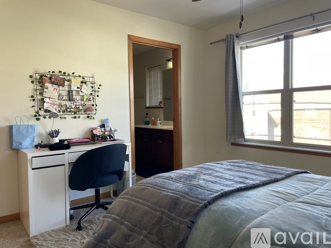 A bedroom with a bed, desk, chair, and window.