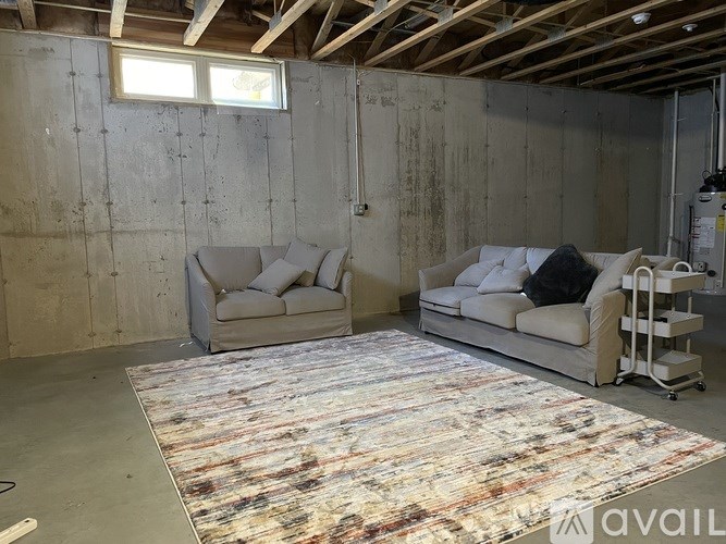 A room with a rug on the floor and two couches.