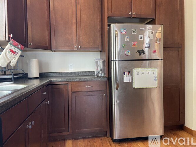 A kitchen with a stainless steel refrigerator and wooden cabinets.