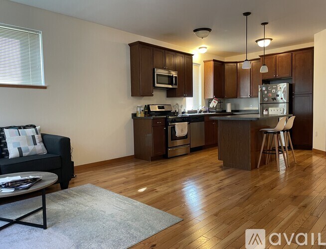 A kitchen with wooden cabinets and a black couch with a grey rug.