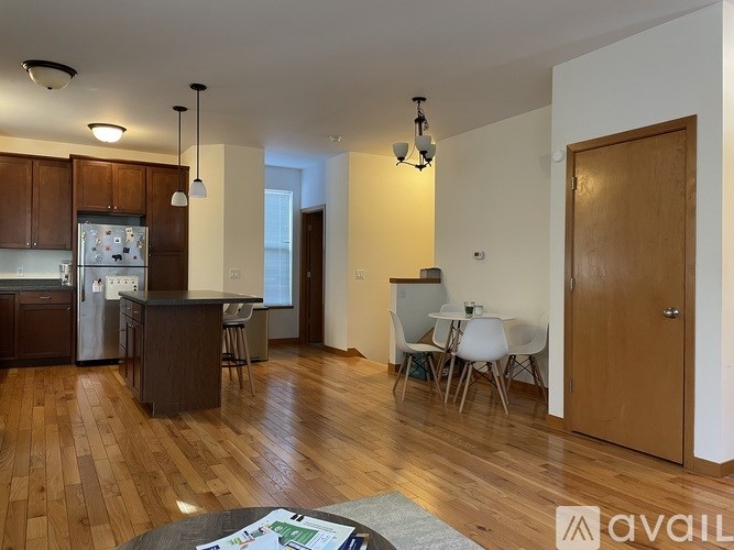 A kitchen with wooden floors and a dining area with white chairs.