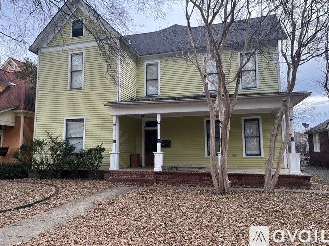 A yellow house with a tree in front.