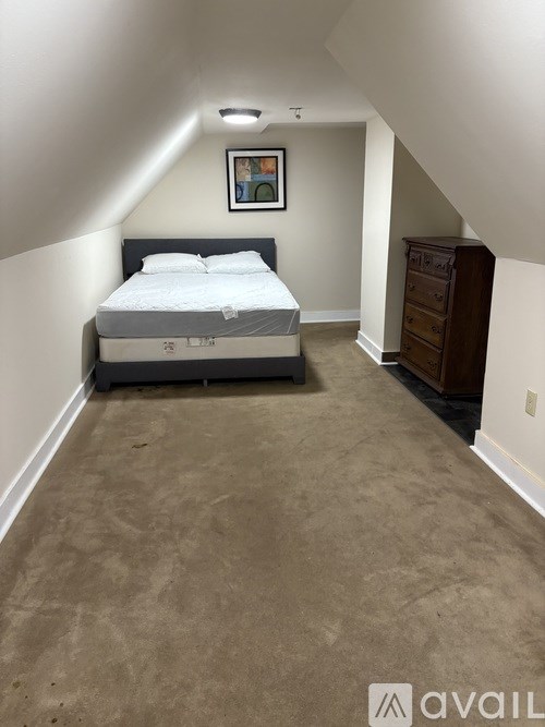A bedroom with a bed, dresser, and a painting on the wall.