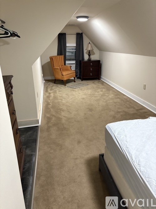 A bedroom with a bed, dresser, and chair.