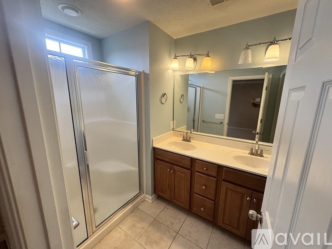 A bathroom with a glass shower door and a sink with a mirror above it.