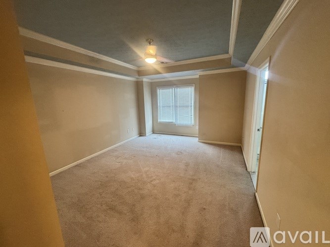 A room with a carpeted floor and a window with blinds.