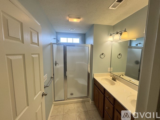 A bathroom with a walk-in shower, double sinks, and a large mirror.