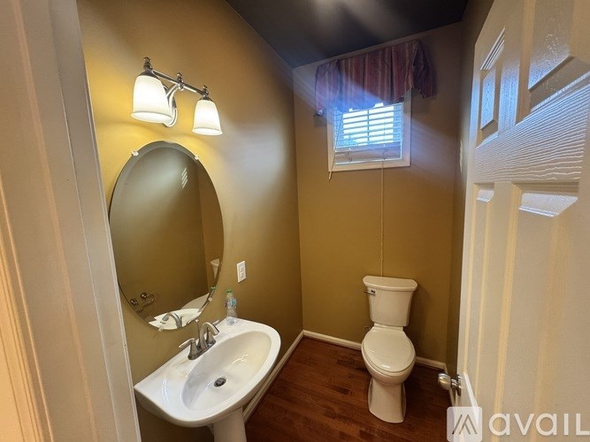 A bathroom with a toilet, sink, and mirror.