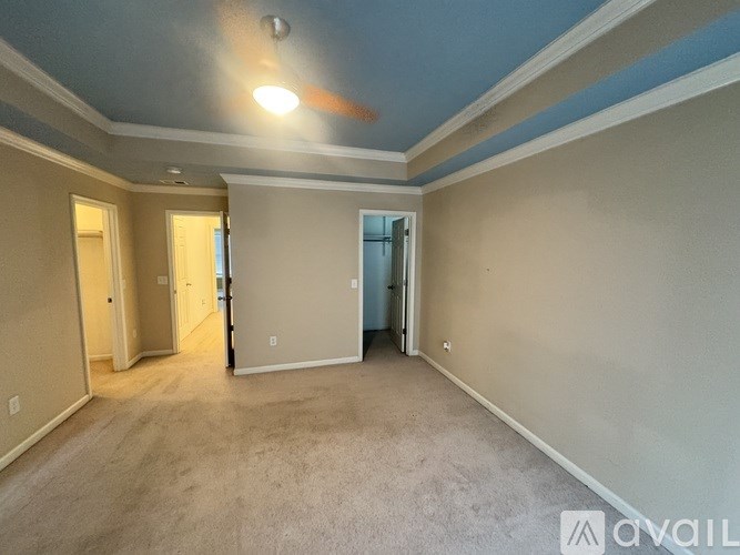 A room with a carpeted floor and a ceiling fan.
